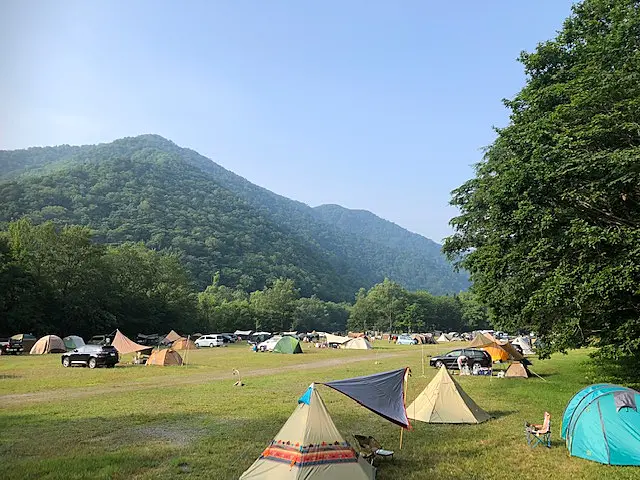 山麓の芝生のキャンプ場に色とりどりのテントがたつ様子