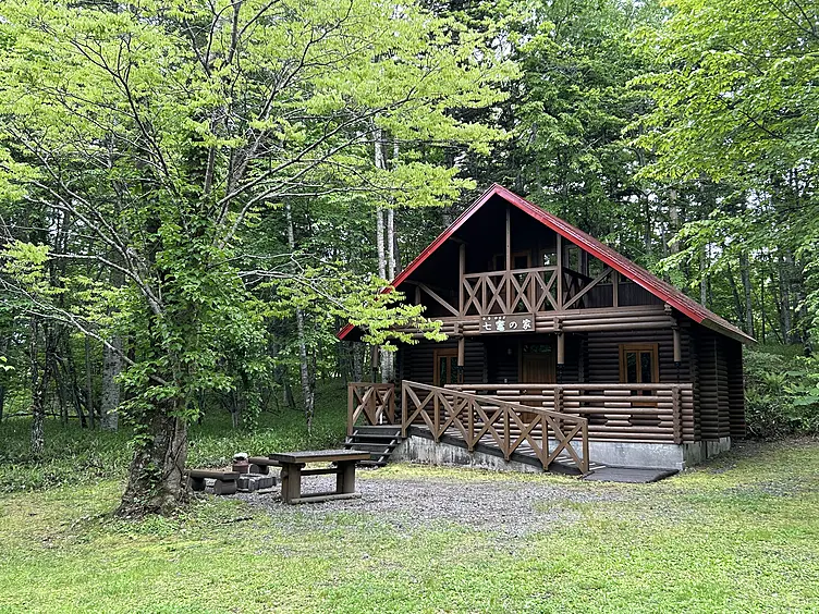 森の中に建つ赤い屋根の2階建てコテージ
