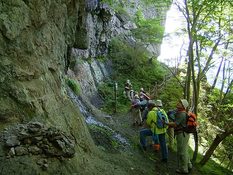 岩が反り立つ登山道を登る人々