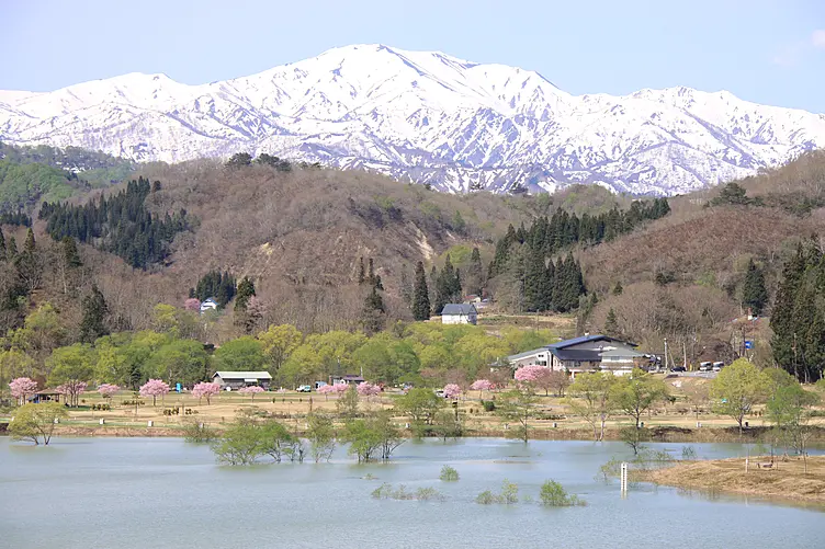 奥に冠雪のある山、手前に川