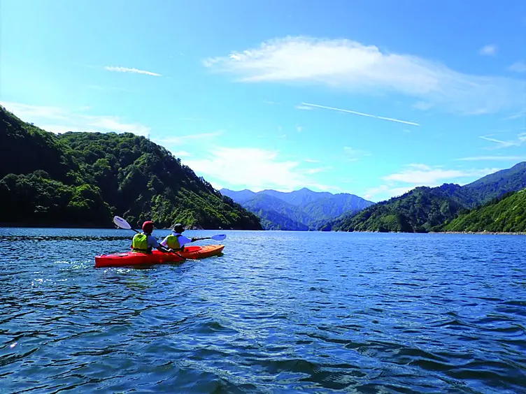 赤いカヤックに乗ってダム湖を漕ぐ人