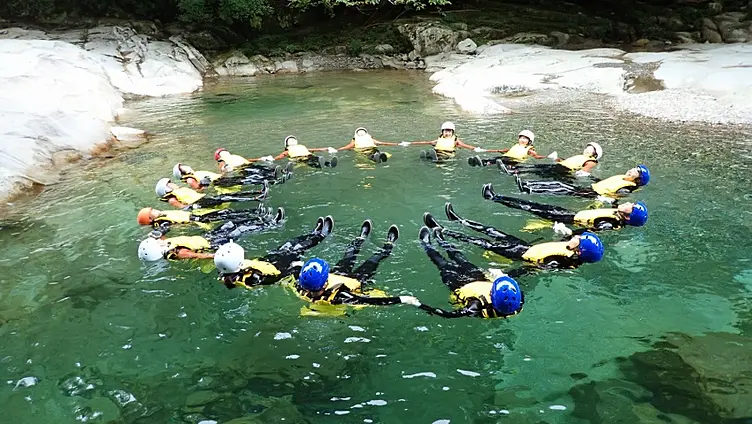 清流の水面にみんなが手を繋ぎ輪になって浮かんでいる