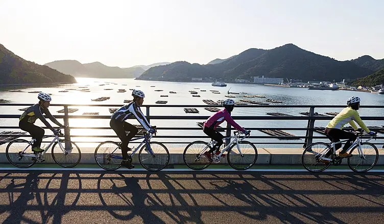 太陽の光で照らされた瀬戸内海に架かる「備前♡日生大橋」を通過するサイクリスト