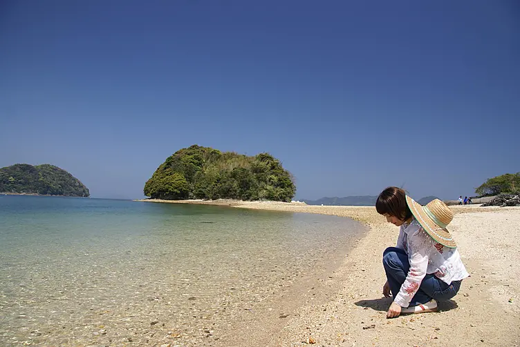 干潮時に陸続きになる真宮島の砂浜にたたずむ女性