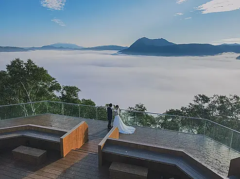雲海の広がる展望テラスでウェディングフォトを撮る人