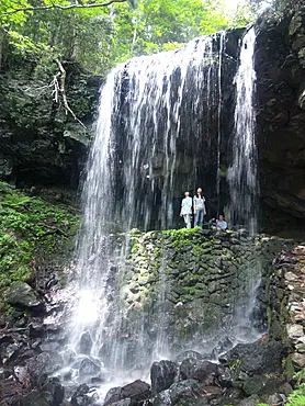 滝から流れ落ちる清水と２人の女性
